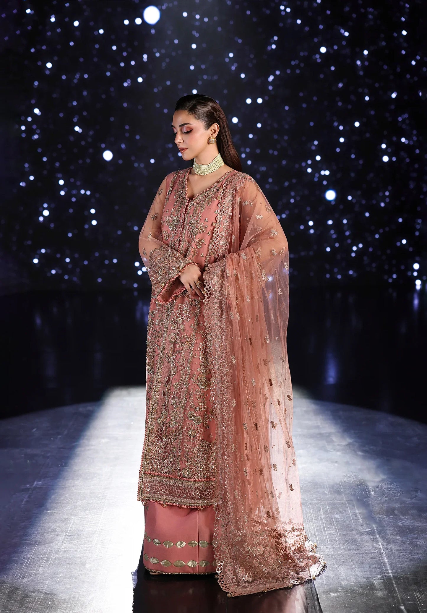 Woman in a traditional pink embroidered outfit on a dark starry night background