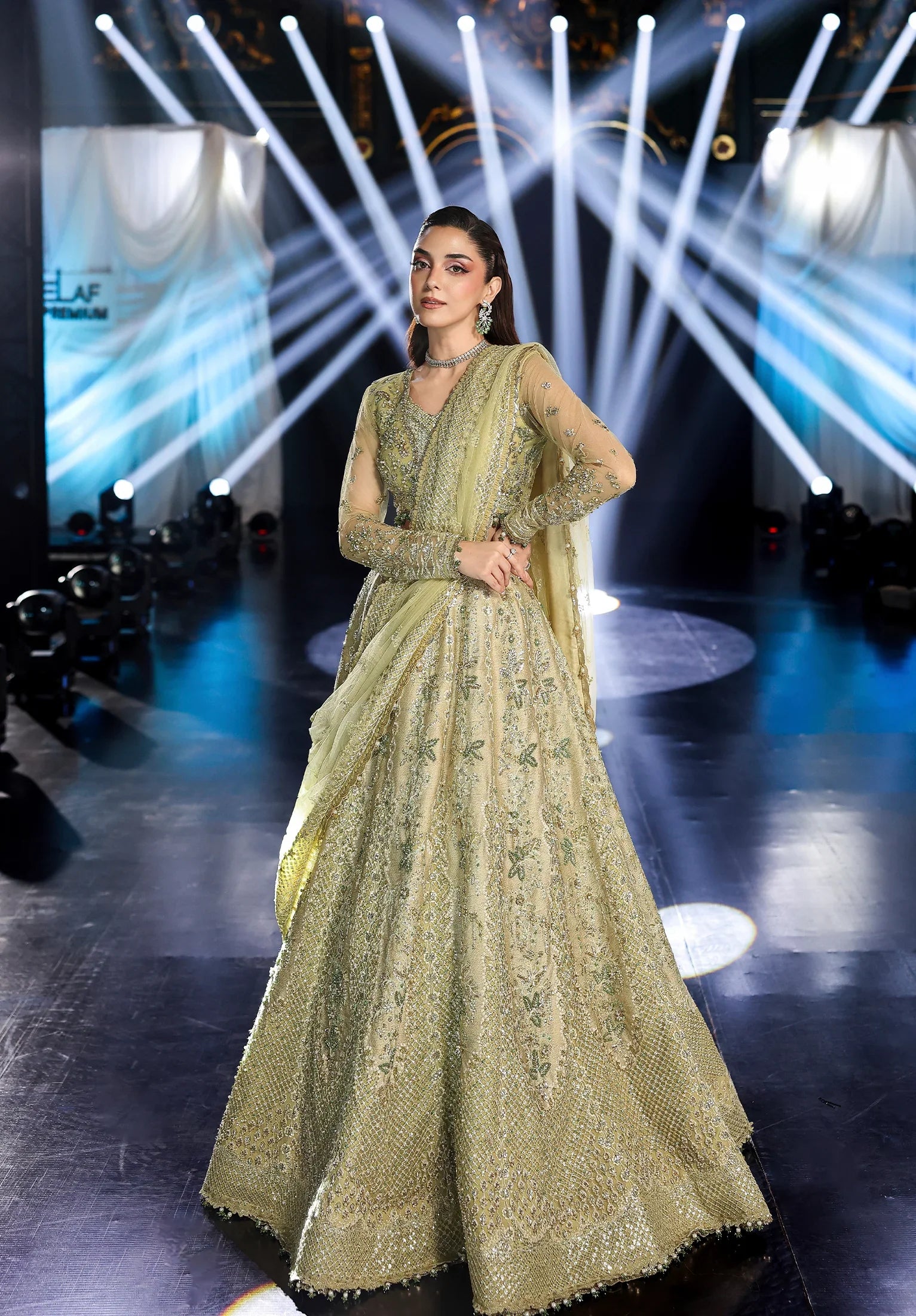 Woman in a green traditional outfit on a stage with bright lights