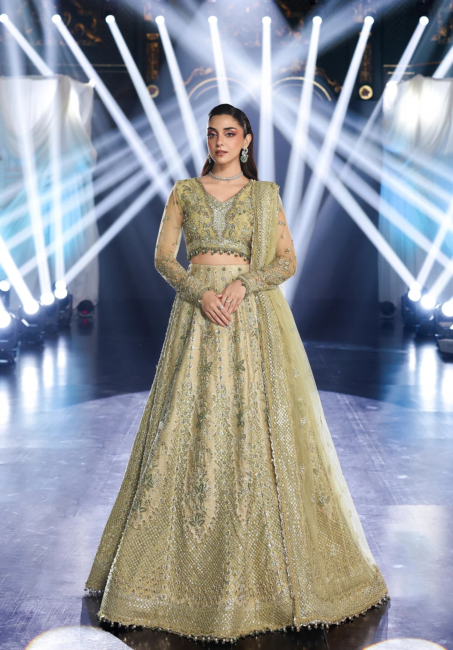 Woman in a traditional embroidered outfit on a stage with bright lights