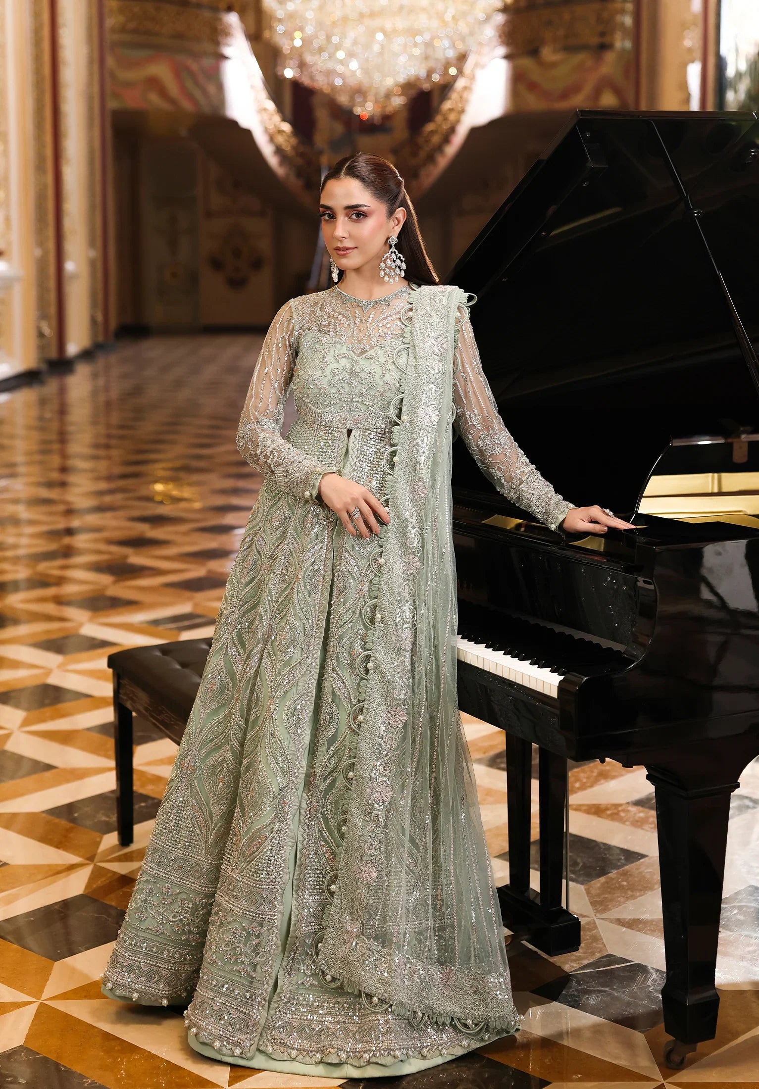 Woman in a traditional outfit standing next to a grand piano in an elegant interior setting.