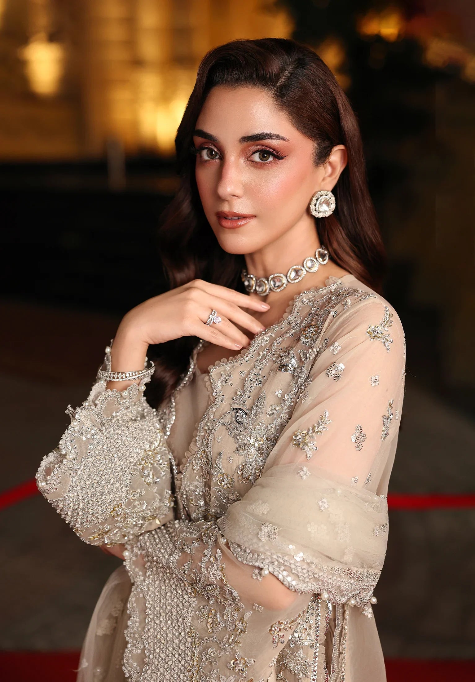Woman in a silver embellished outfit on a red carpet with Elaf Stardom Handwork