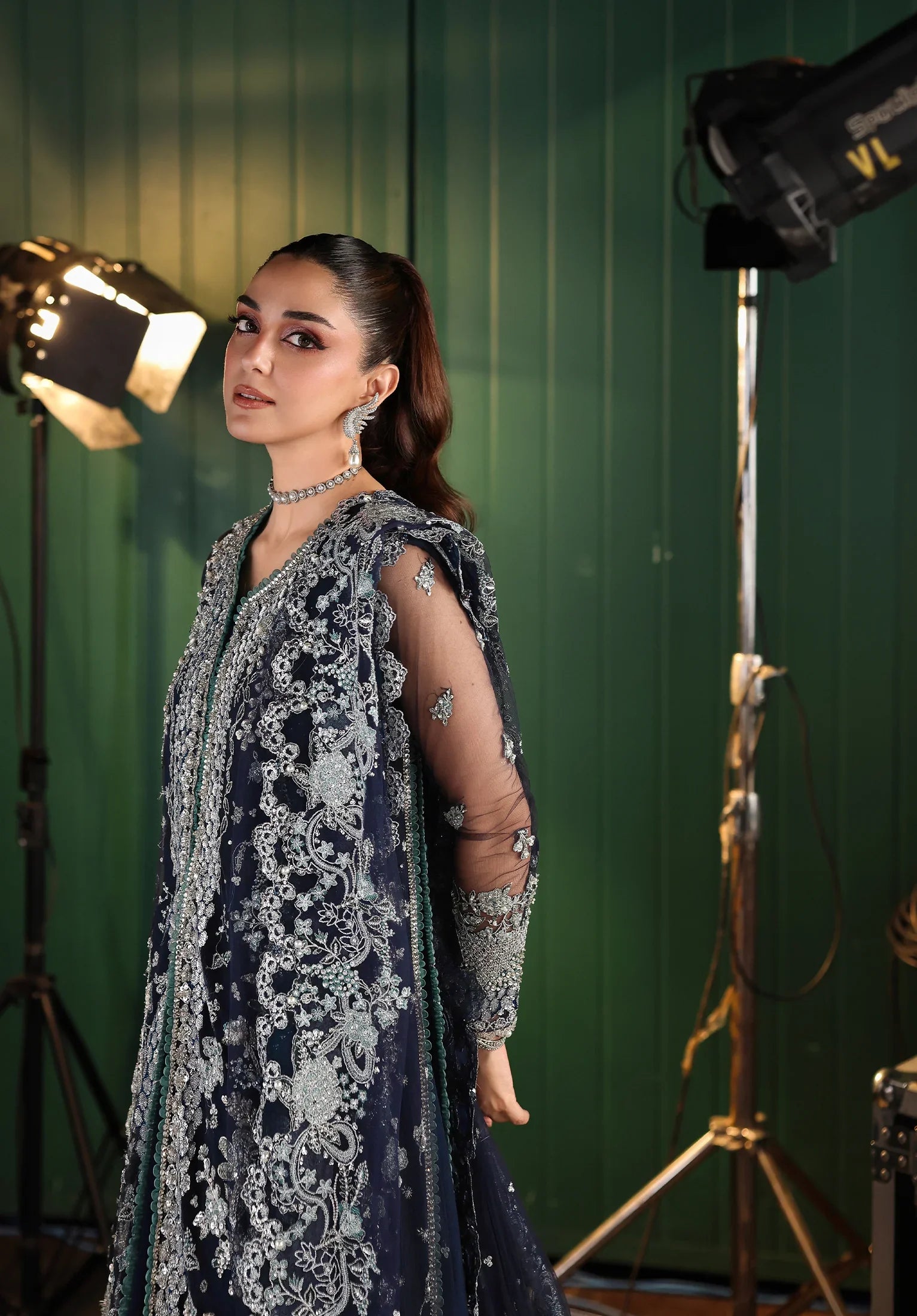 Woman in an embroidered outfit standing in a studio with green screen background
